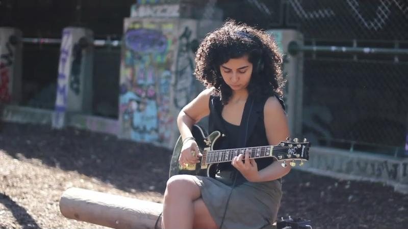 Nazanin spielt E-Gitarre vor einer Graffitiwand